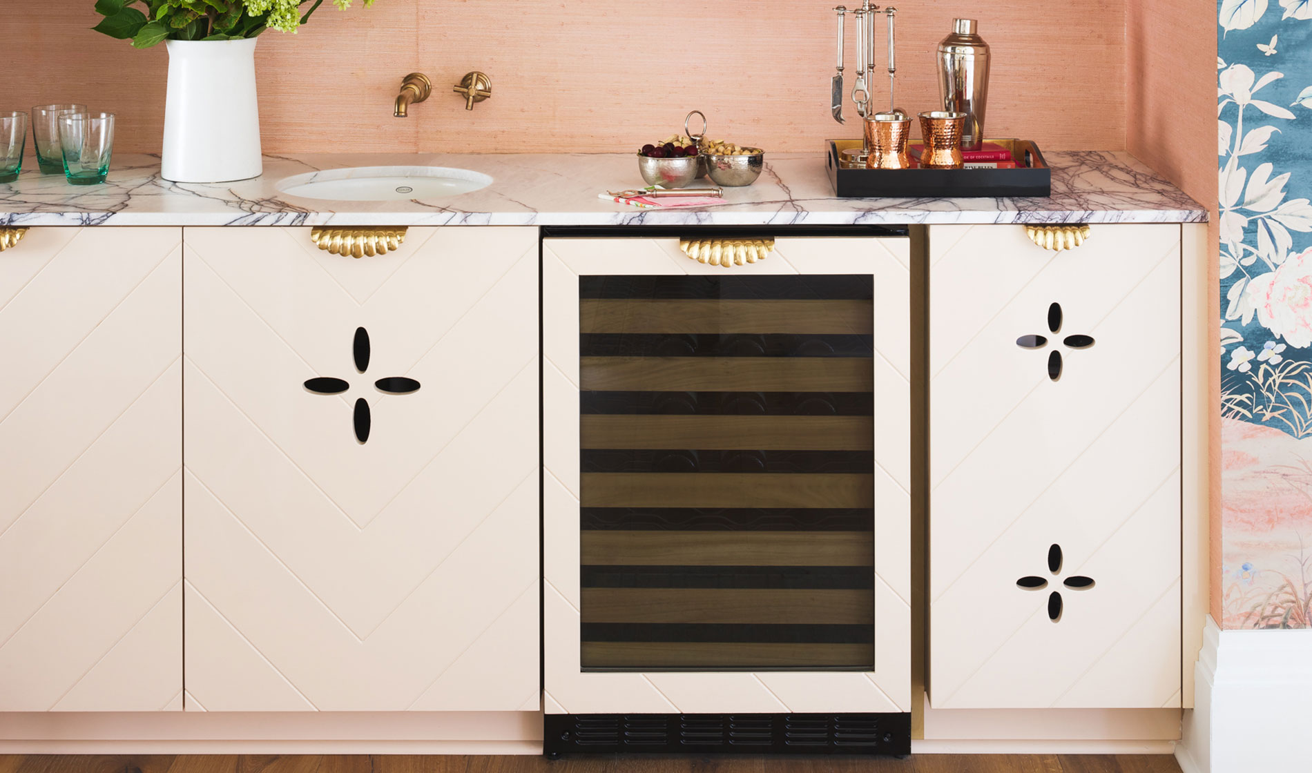 Bar with built-in Monogram wine reserve with pink cabinets and floral wallpaper